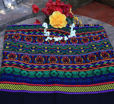 Güipil Kem Textiles, fondo: negro, con figuras en el centro de tonalidades verdes, azul, rojo, amarillo morado y lilas