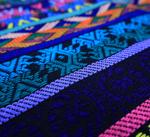 Güipil Kem Textiles, fondo: negro con figura en el centro de colores verde, lila, fucsia, rojo, anaranjado, mostaza azul, amarillo