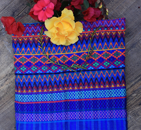 Güipil para niña, Kem Textiles, fondo: franjas azules, con figura geométrica en el centro de color magenta y anaranjado