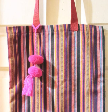 Bolsa de tela en tonos rosa con fondo negro y cinta de color.