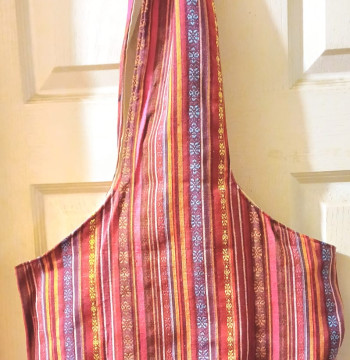 Bolsa de tela con diseños y colores en tonos rojos con cincho ancho y forro