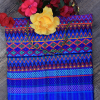 Güipil para niña, Kem Textiles, fondo: franjas azules, con figura geométrica en el centro de color magenta y anaranjado
