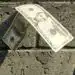 Dinero en billetes de diez y cinco dólares estadounidenses sobre suelo de ladrillo.
