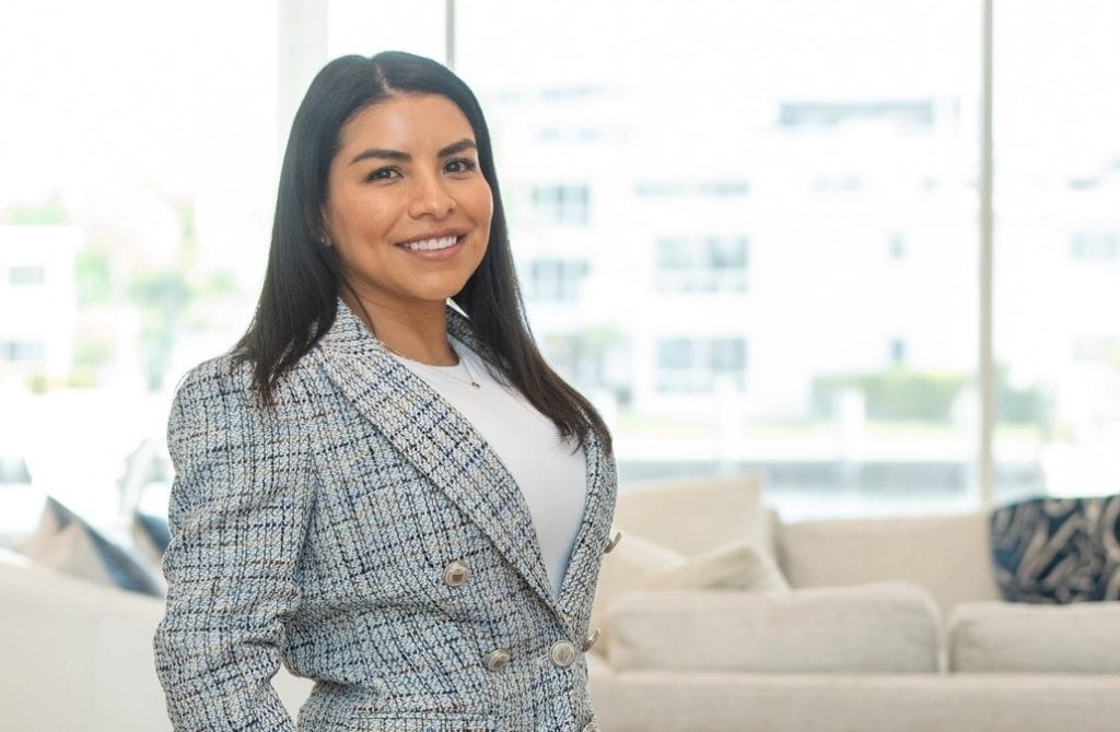 Mujer migrante en oficina moderna, símbolo de éxito y empoderamiento para la comunidad migrante en América Latina. – SoyMigrante.com REVISTA