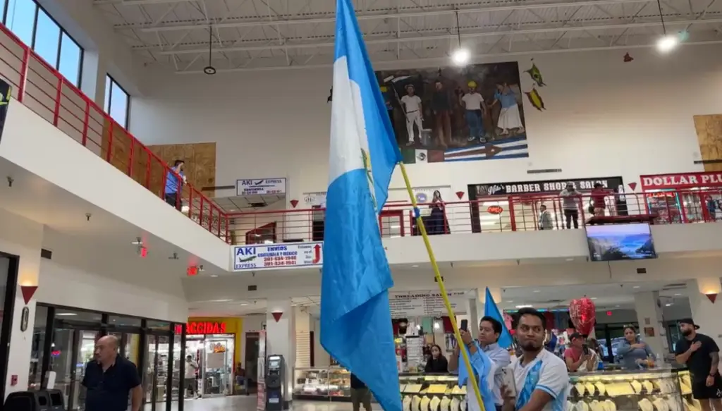 El canto del himno nacional frente a la bandera de Guatemala fue el inicio de esta protesta pacífica de migrantes en contra del acoso a la democracia en el país. – SoyMigrante.com REVISTA