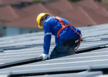 Trabajador instalando paneles solares en tejado para energías renovables en México, sostenibilidad y energía solar.
