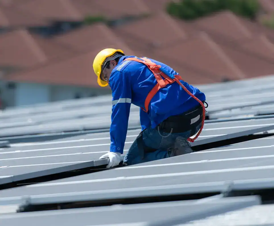 Imagen genérica de un trabajador migrante instalando paneles en un techo, cuyo trabajo posiblemente genera remesas familiares en dólares para Guatemala – SoyMigrante.com REVISTA Trabajador instalando paneles solares en tejado para energías renovables en México, sostenibilidad y energía solar. – SoyMigrante.com REVISTA