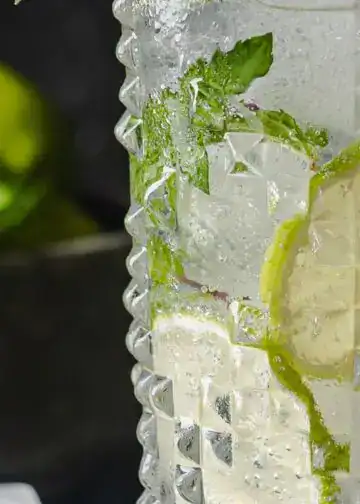 Refresco de limón con menta en vaso de vidrio con diseño, hielo y condensación, ideado para refrescar en verano, ideal para eventos y bebidas refrescantes. – SoyMigrante.com REVISTA