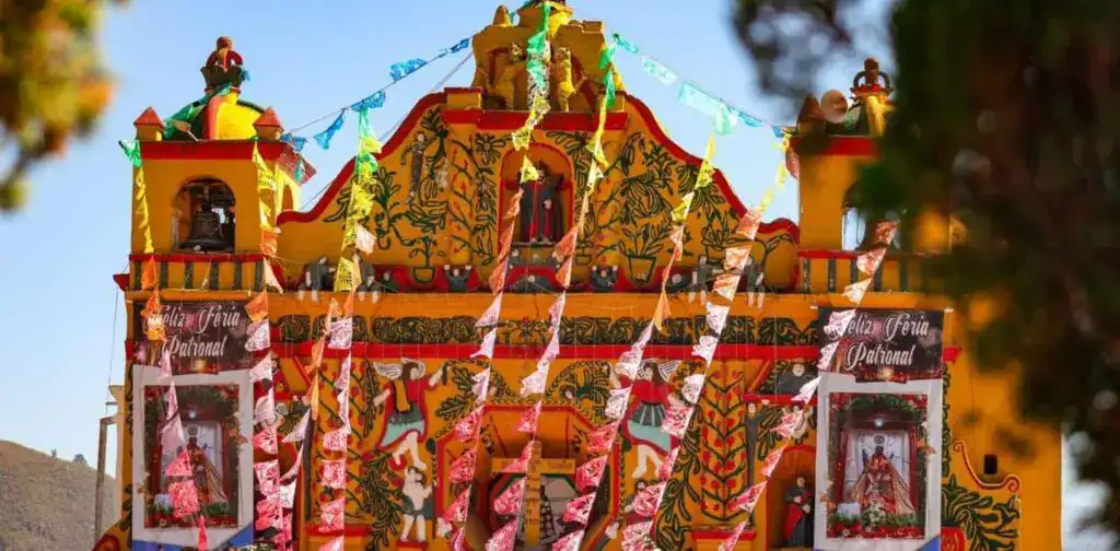 Columna decorada y altar de fiesta patronal en un festival tradicional mexicano, con banderines y elementos culturales, reflejando celebración y cultura popular. – SoyMigrante.com REVISTA