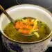 Receta chapina caldo de res al estilo guatemalteco. Caldo de verduras, sopa nutritiva y saludable con zanahorias, pasta y hierbas frescas en una taza artesanal.