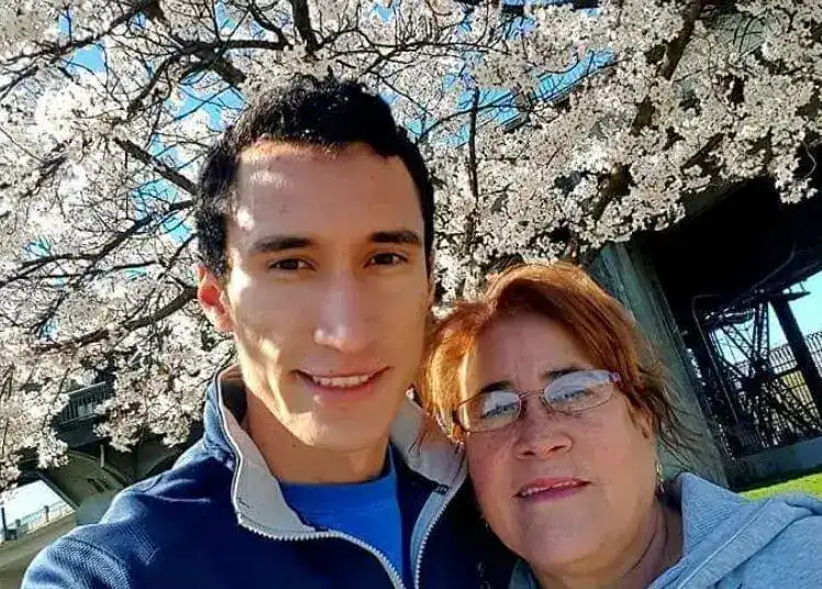 Retrato de un joven y una mujer en un parque con árboles en flor, celebrando la cultura y comunidad migrante en una sensación de unión y alegría.