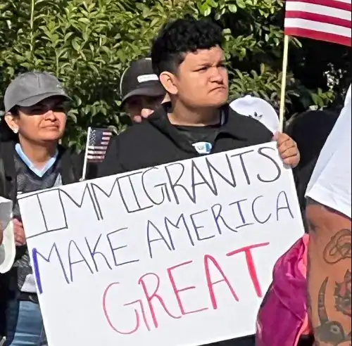 Inmigrantes con cartel "Immigrants make America great", protestando en una marcha en EE.UU. manifestando apoyo a la inmigración y el impacto positivo de los migrantes en América.
