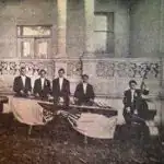 Retrato de músicos mexicanos en uniforme formal tocando instrumentos tradicionales en un evento histórico, representando la cultura y el talento artístico en México.