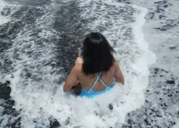 Nina en la playa siendo parte de una historia de migrantes, simbolizando el viaje y la esperanza en el contexto de la migración internacional.