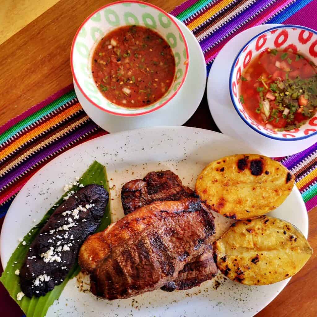 La ventaja del churrasco chapín es que existen muchas opciones fáciles de conseguir: frijolitos, papas asadas, chirmol. Fotografía cortesía Lourdes Lorena Donis Sanhueza – SoyMigrante.com REVISTA