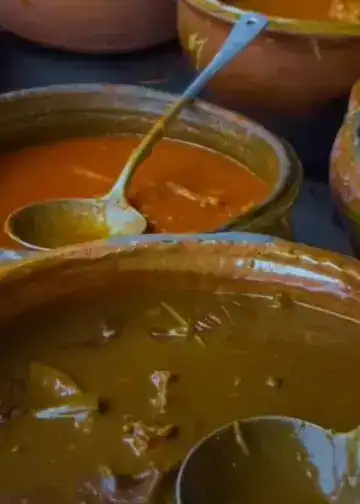Guiso tradicional mexicano en tinajas de barro con cuchara, comida casera y auténtica, cercana a la gastronomía mexicana, en un mercado o cocina tradicional, representación de la cultura culinaria de México. – SoyMigrante.com REVISTA