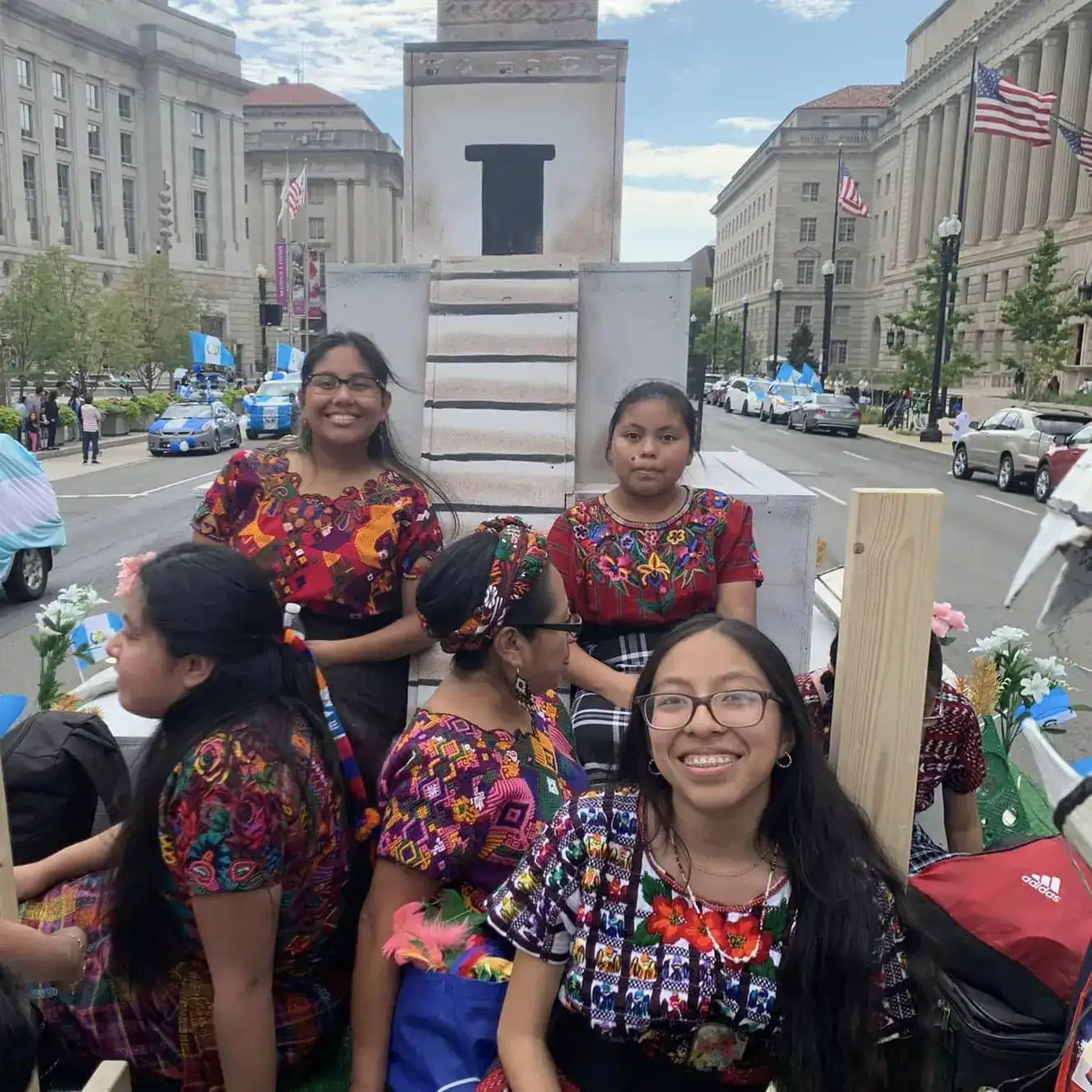 Ejemplo de hijas migrantes con vestimenta típica durante una manifestación en una calle de ciudad estadounidense.
