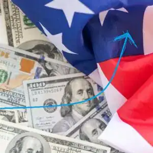 Dinero en billetes de dólares y bandera de EE.UU., símbolo de migración y economía internacional. – SoyMigrante.com REVISTA