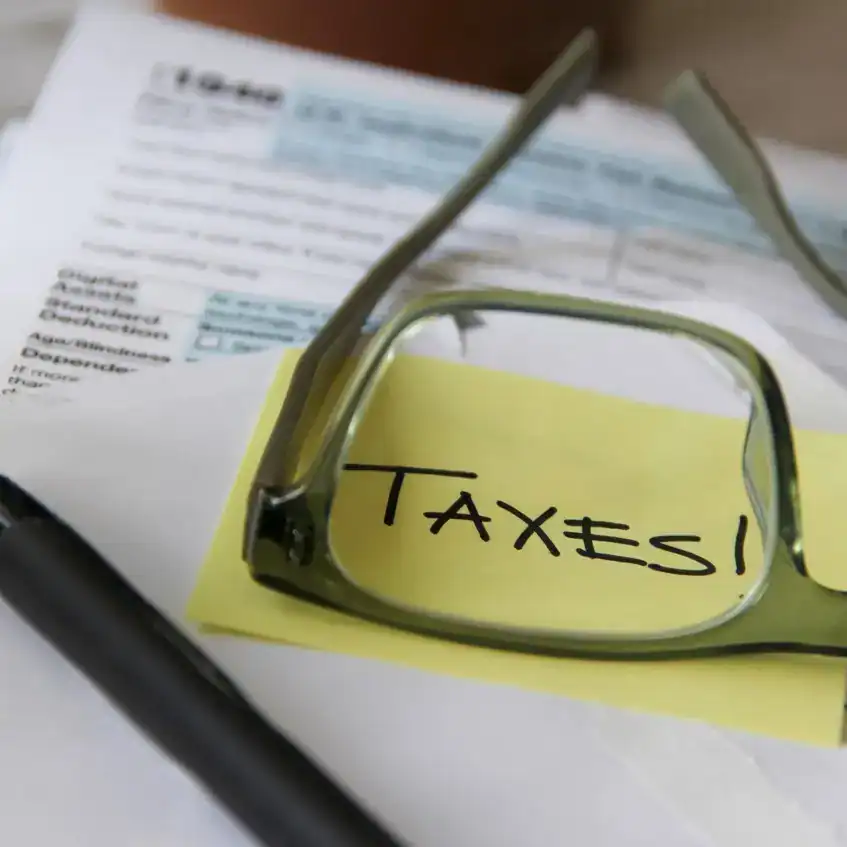 Concentración en impuestos para migrantes, con gafas y documentos, en la revista SoyMigrante.com.