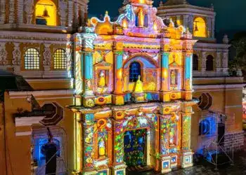 Vivienda antigua decorada con proyecciones de luz y color en la noche, destacando detalles arquitectónicos y efectos visuales para eventos culturales y festivales en México.
