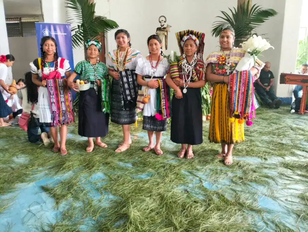 Niñas indígenas con trajes tradicionales en acto cultural, representando la diversidad y riqueza cultural de las comunidades originarias en la revista SoyMigrante.com REVISTA.