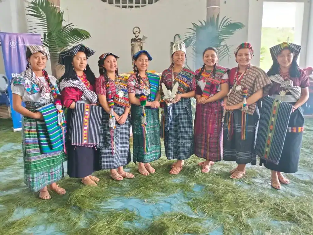 Vestido tradicional indígena de Guatemala, celebración cultural, mujeres con trajes coloridos y accesorios étnicos en evento cultural.