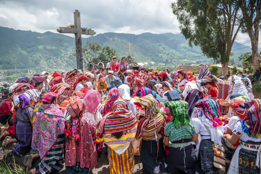 Personas tradicionales de la comunidad indígena en una celebración cultural en un entorno montañoso en México, vestidas con trajes coloridos y sombreros típicos, en un evento que refleja raíces culturales y identidad. – SoyMigrante.com REVISTA