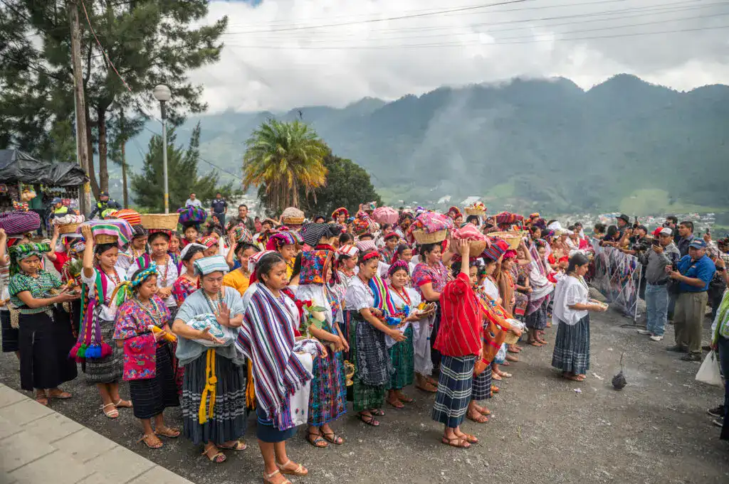 Campesinas indígenas en celebración tradicional en México, vestimentas coloridas y cultura ancestral en un entorno de montañas y naturaleza. – SoyMigrante.com REVISTA