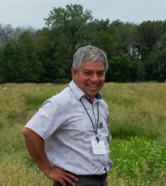 Persona sonriendo en un campo verde, representando la comunidad migrante y la importancia de la integración en la sociedad. – SoyMigrante.com REVISTA