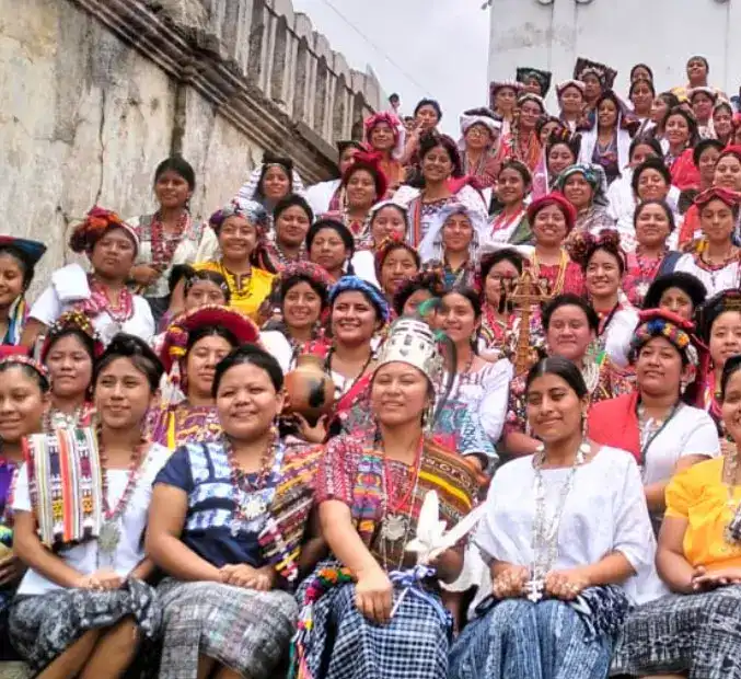 Multitud de mujeres indígenas vestidas con trajes tradicionales en una reunión cultural en un entorno urbano. – SoyMigrante.com REVISTA