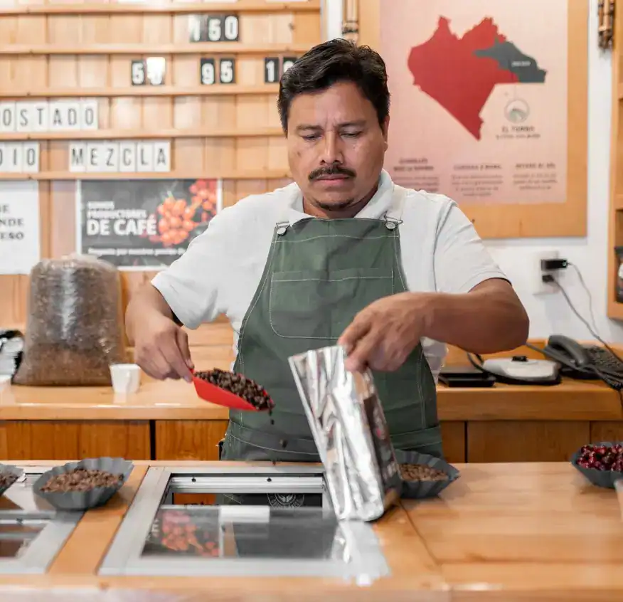Café de especialidad preparado por un barista en una cafetería, enfocándose en calidad y sostenibilidad, promoviendo el comercio justo y la cultura del café en América Latina.