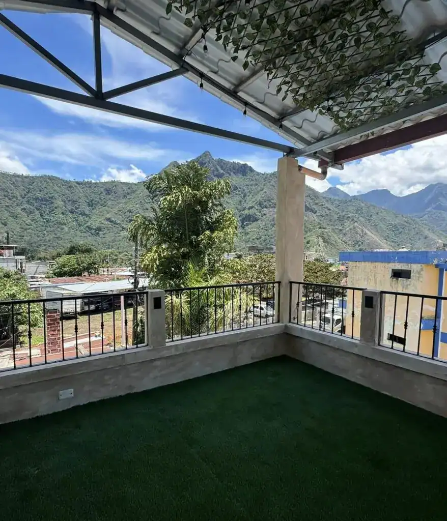Vistas panorámicas de montañas desde balcón decorado con césped artificial, ideal para espacios exteriores y actividades al aire libre. – SoyMigrante.com REVISTA