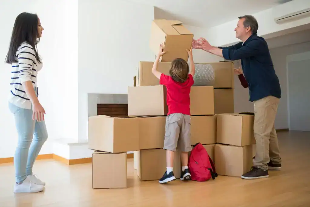 Caja de mudanza con un adulto y un niño en una vivienda, preparando para cambiar de hogar, reflejando migración y nuevas oportunidades.