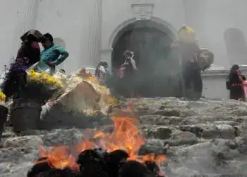 Fuego en las escaleras de una iglesia durante un ritual religioso en contexto migrante en América Latina.