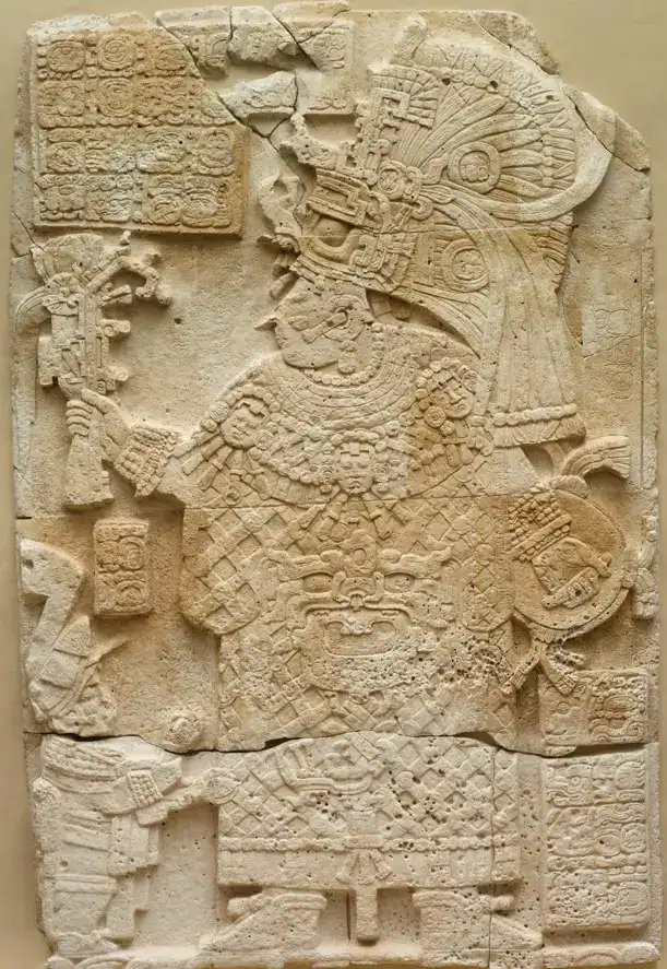 La estela 33 de El Perú Waká presenta a la reina Kábel de cuerpo entero, con un traje que le cubre todo el cuerpo, un tocado de plumas, joyas de jade y un cetro sagrado. Frente a ella hay un enano, posiblemente un sirviente. (Fotografía Museo de Arte de Cleveland bajo licencia Creative Commons) – SoyMigrante.com REVISTA