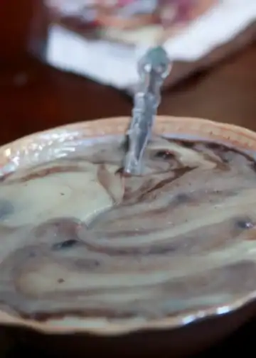 Arroz con leche en un plato, con leche y algunos ingredientes mezclados, en una mesa de comida tradicional mexicana.