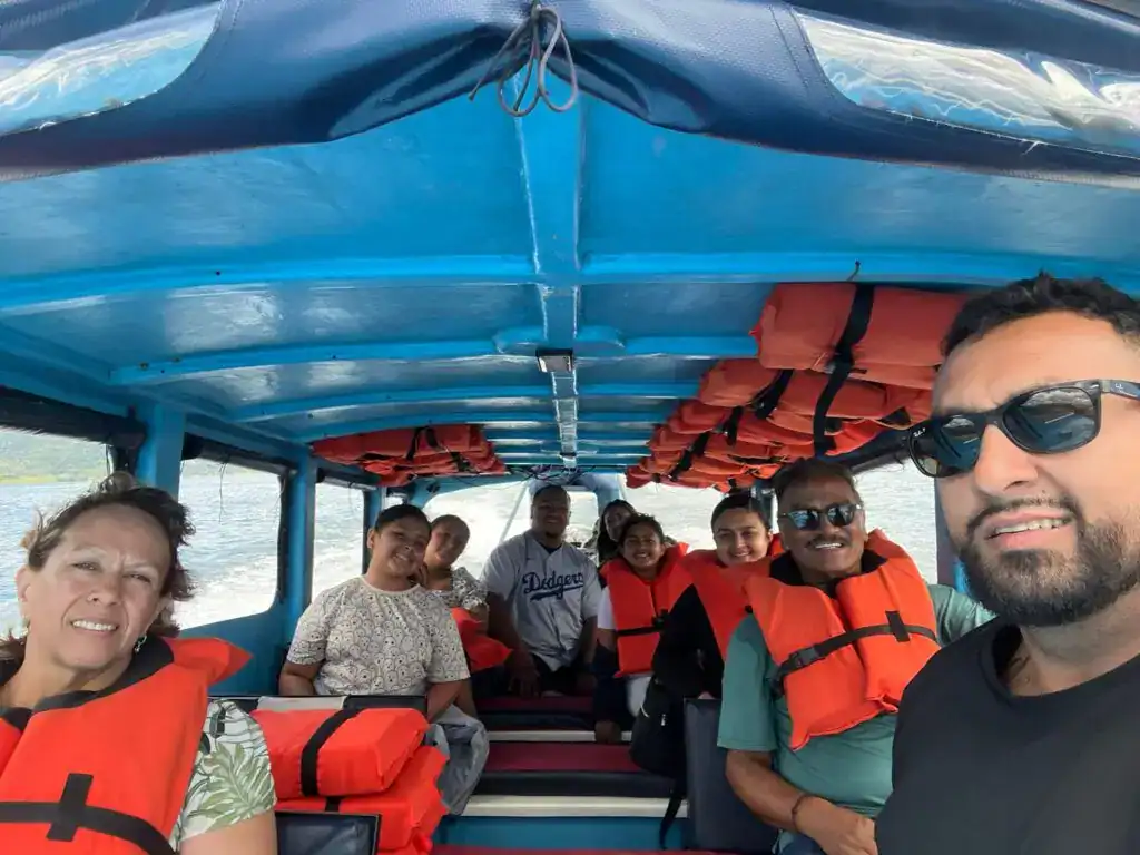 Barco con migrantes y turistas en un viaje por el agua, todos con chalecos salvavidas, en un entorno natural, promoviendo experiencias de migración y turismo responsable. – SoyMigrante.com REVISTA