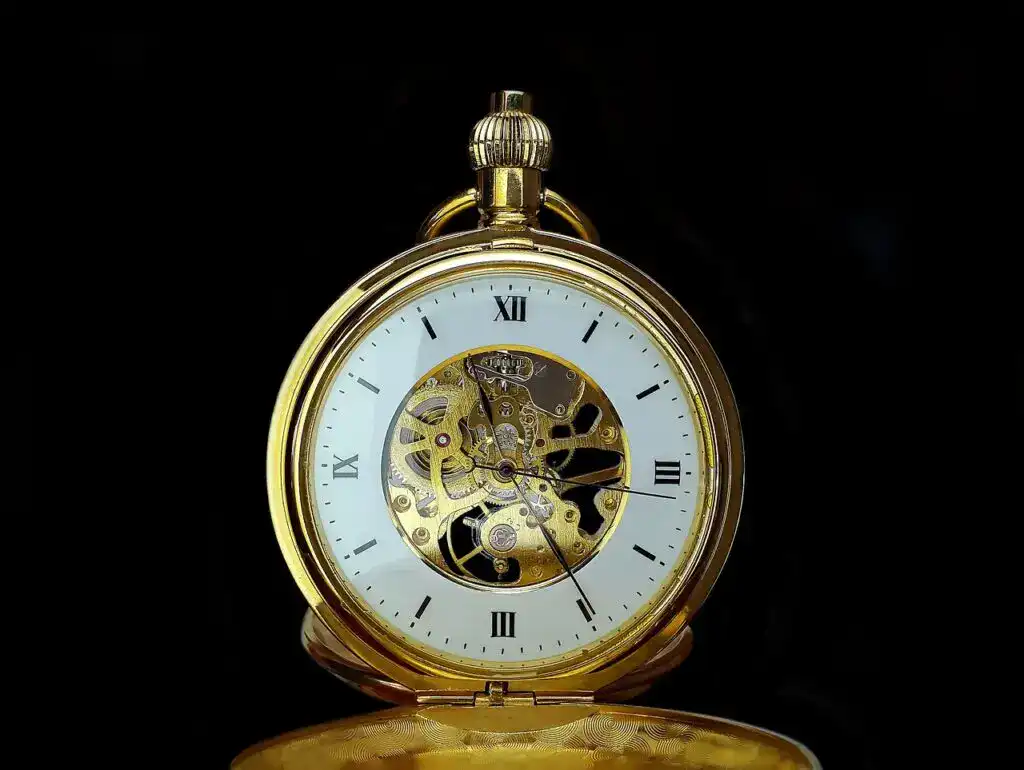Reloj de bolsillo dorado con mecanismo visible, simbolizando el paso del tiempo y la historia de migrantes en la República Mexicana y Estados Unidos. – SoyMigrante.com REVISTA