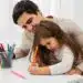 Diálogo entre padre e hija, escribiendo en la mesa, con materiales de oficina y útiles de colores, promoviendo la educación infantil y el acompañamiento familiar.