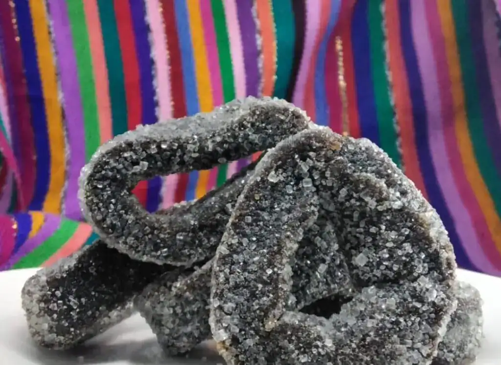 Sabores tradicionales de México: piedras de azúcar negras en forma de rosquilla con azúcar cristalizada, perfecta para celebrar festividades y compartir en comunidad. – SoyMigrante.com REVISTA