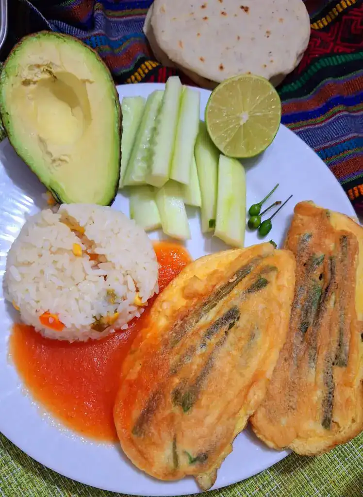 Receta tradicional mexicana con pescado frito, arroz, guacamole, pepino y salsa de tomate, perfecta para disfrutar la gastronomía de México en cada bocado.