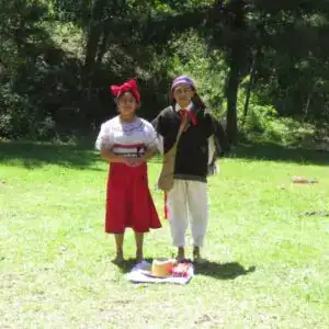 Jovenes con indumentaria akateko, participando en una celebración cultural al aire libre en un entorno natural. Idioma y etnia maya akateko o maya akateka
