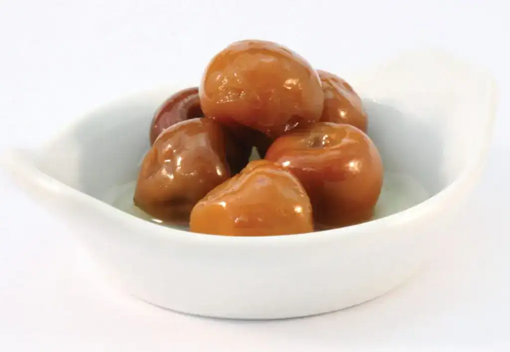 Dátiles caramelizados en un bol blanco, muestra un fruto seco preparado con recipientes tradicionales, destacando por su textura y sabor dulce, ideal para recetas y snacks saludables. – SoyMigrante.com REVISTA