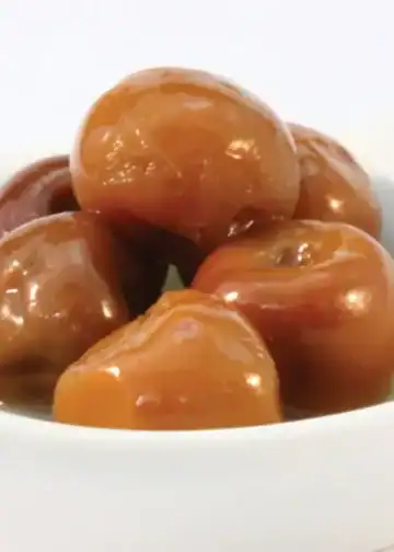 Dátiles caramelizados en un bol blanco, muestra un fruto seco preparado con recipientes tradicionales, destacando por su textura y sabor dulce, ideal para recetas y snacks saludables.
