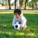 Niña jugando con balón de fútbol en parque, disfrutando de actividades deportivas para niños. – SoyMigrante.com REVISTA