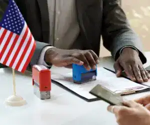 Tarjeta de inmigración en EE.UU. y sello de ingreso con bandera estadounidense en una oficina migratoria. Documentación migratoria y proceso de visas para migrantes en Estados Unidos.