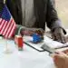 Tarjeta de inmigración en EE.UU. y sello de ingreso con bandera estadounidense en una oficina migratoria. Documentación migratoria y proceso de visas para migrantes en Estados Unidos.