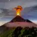 Vista del volcán en erupción con columnas de humo y lava illuminated por la noche, símbolo del poder de la naturaleza y la actividad volcánica en América Central.