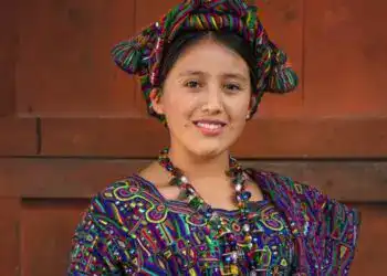 Niña indígena con vestimenta tradicional y accesorios coloridos, representando cultura y identidad en comunidades migrantes en América Latina.
