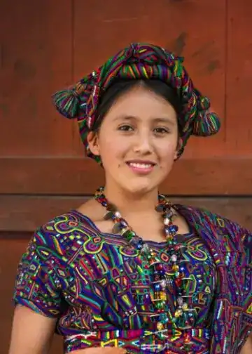 Niña indígena con vestimenta tradicional y accesorios coloridos, representando cultura y identidad en comunidades migrantes en América Latina.